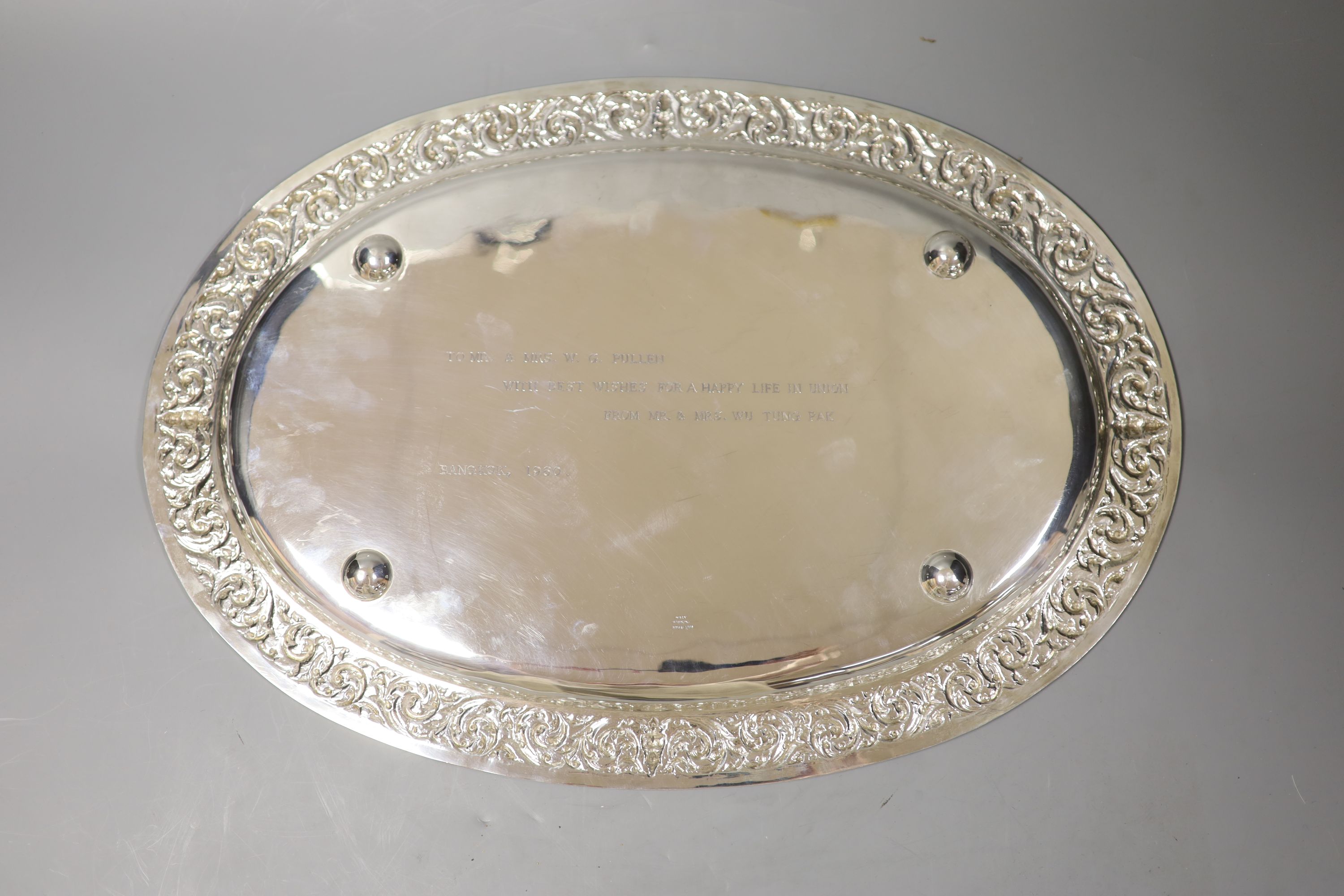 A Thai Sterling white metal oval dish with repousse decoration on four stud feet,